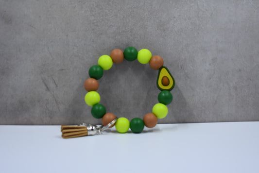 Crafted from silicone beads, this Keychain Wristlet features a faux leather tassel and a prominent Avocado focal bead.