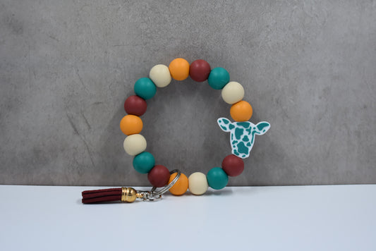 From our cow collection we have this Wristlet keychain made from silicone beads with cute teal cow with a faux leather tassel.